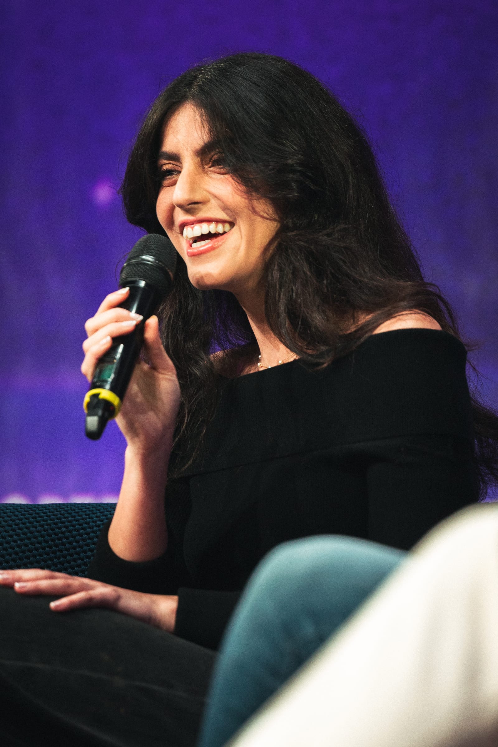 Speaker laughing on stage, mic in hand